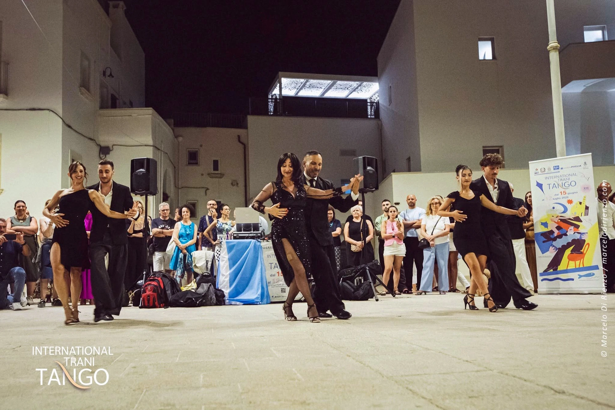 Piu' coppie di tango danzano in piazza davanti agli spettatori